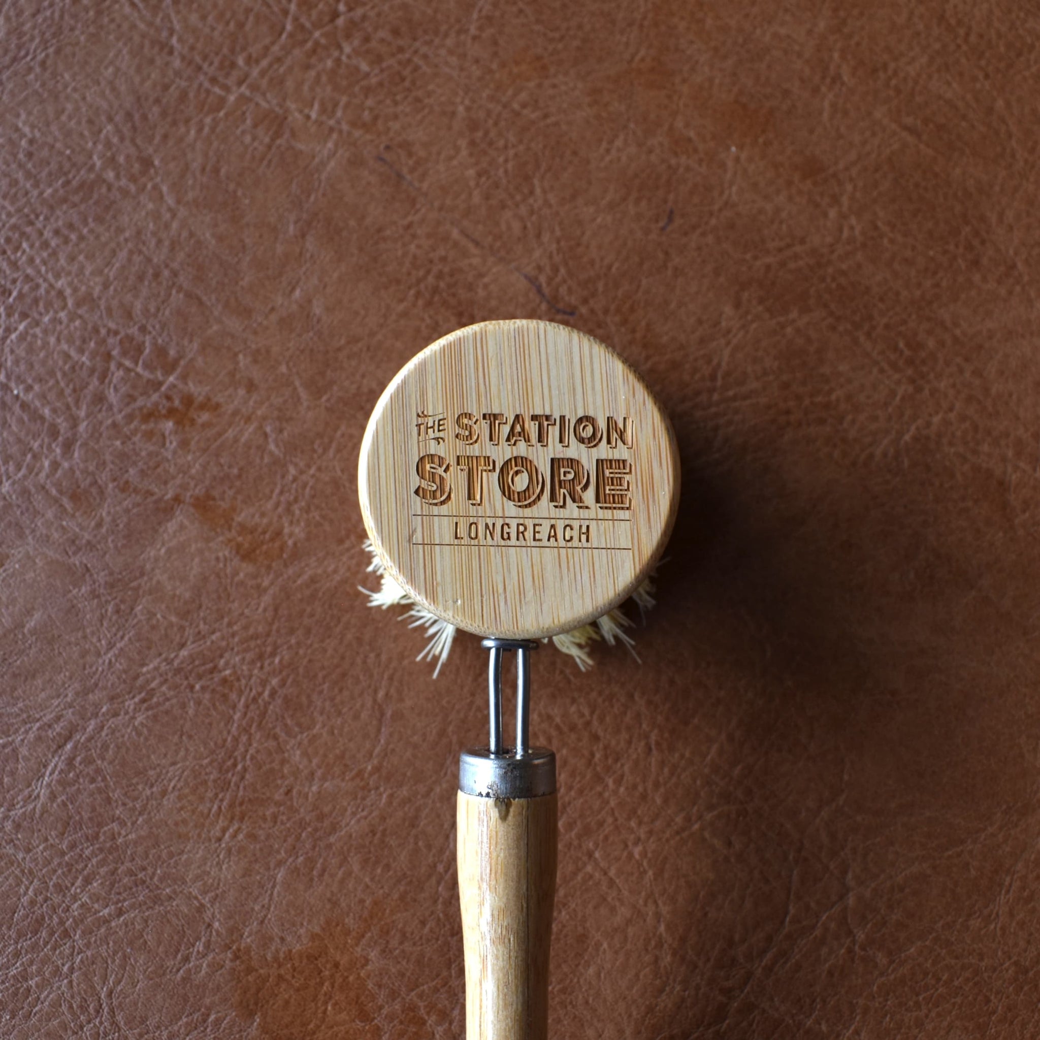 Close up of Bamboo Dish Brush with removable head and long handle featuring the Station Store branding.