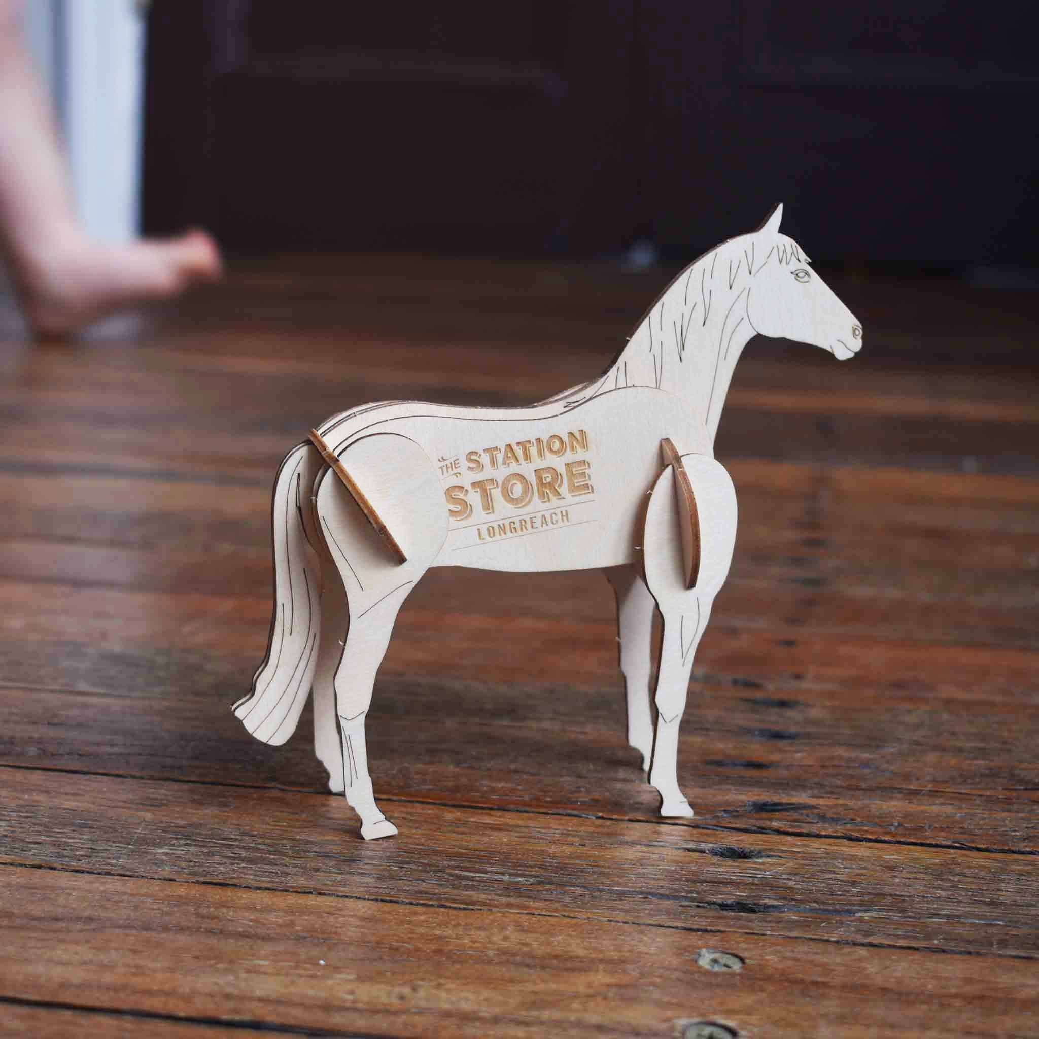 Wooden horse model with 'The Station Store Longreach' branding on a basswood surface.