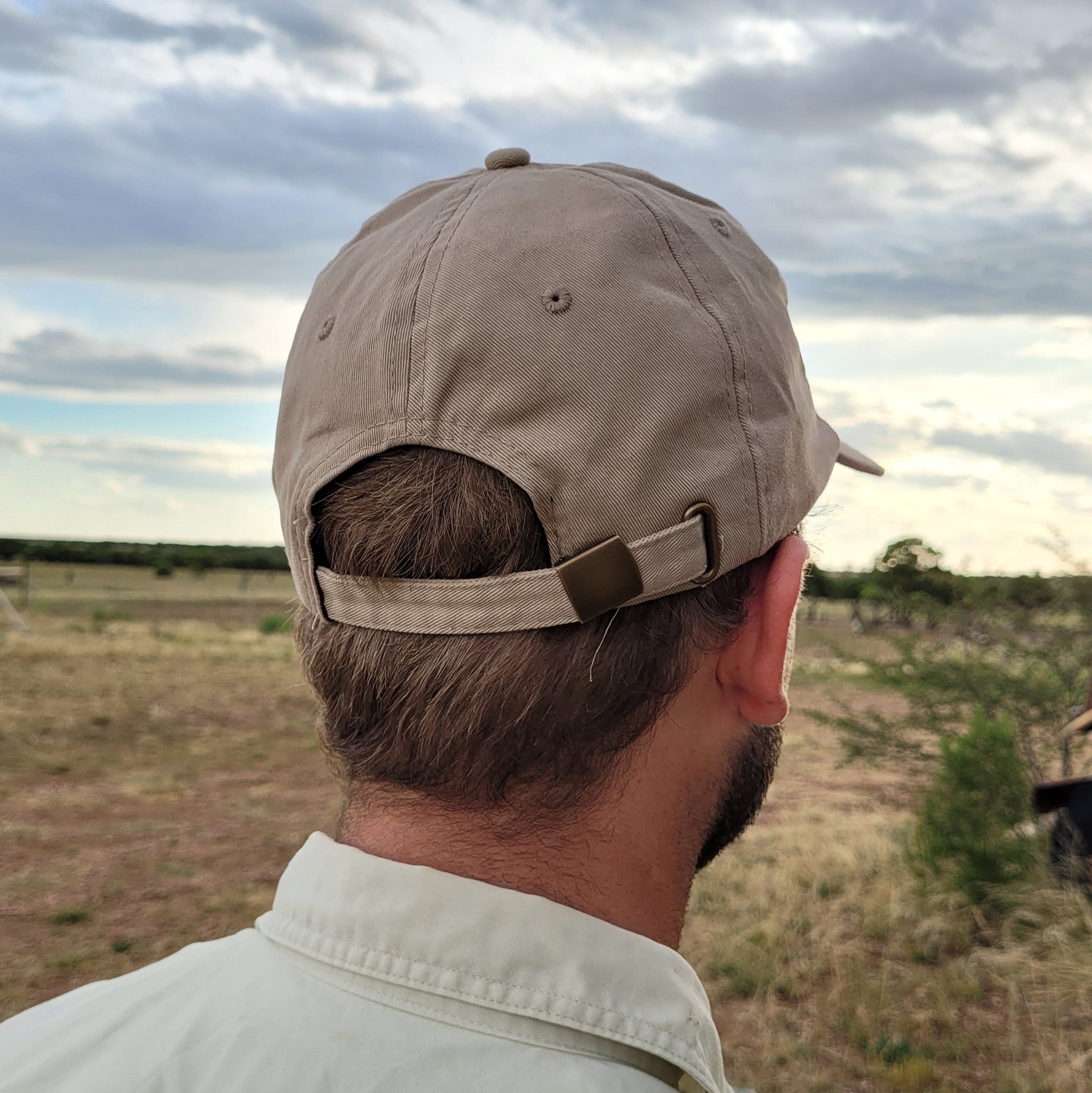 The Station Store cap brushed chino twill in brown. Person wearing cap displaying the adjustable strap backing.