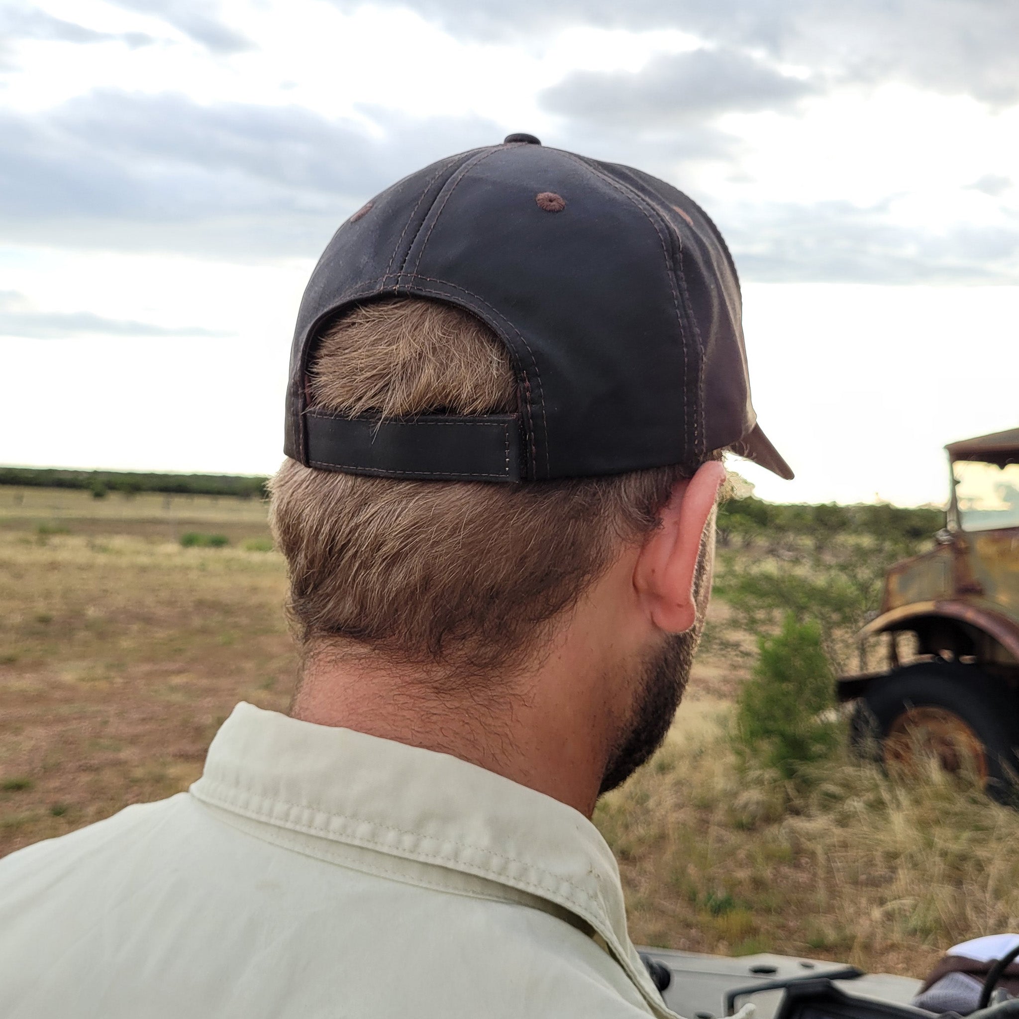 Kinnon and Co brown oilskin look cap on person displaying velcro closure.