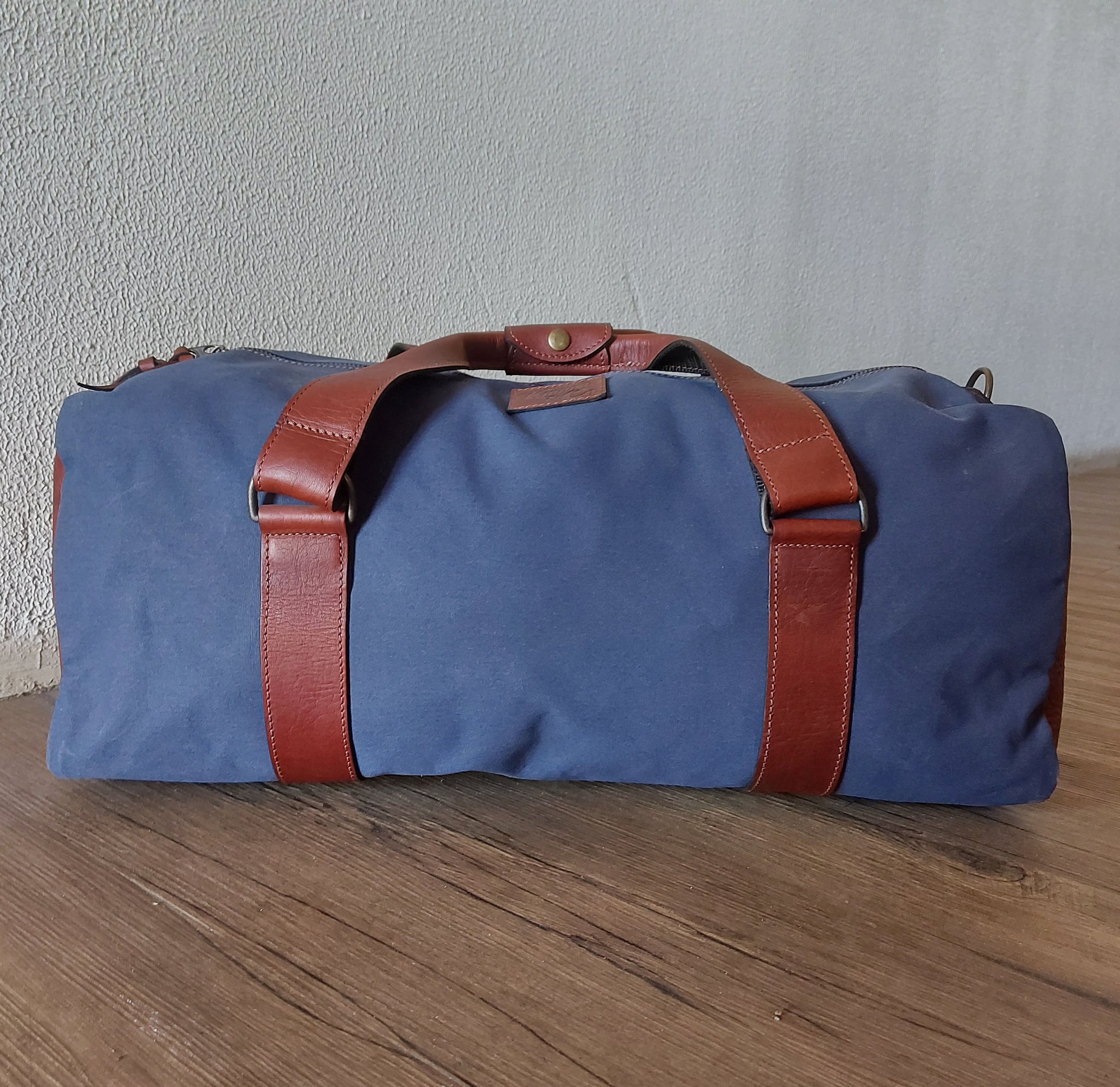 Kinnon and Co branded blue canvas kit bag with tan leather straps