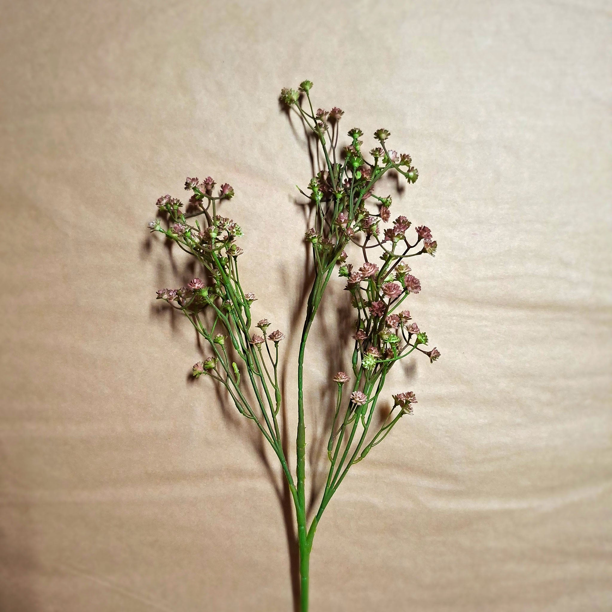 Faux flower display of babys breath in a dusty pink colour with bright green stems