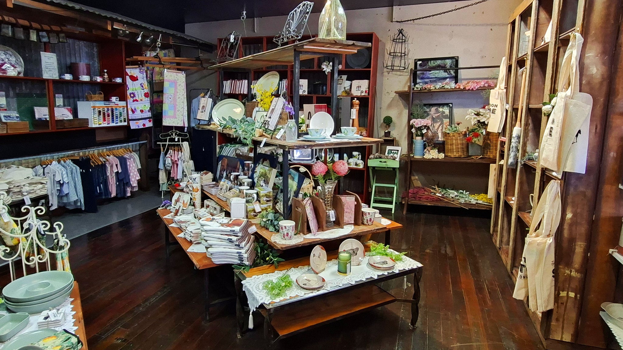 Interior of a store with various products on display, including clothing and home decor items.