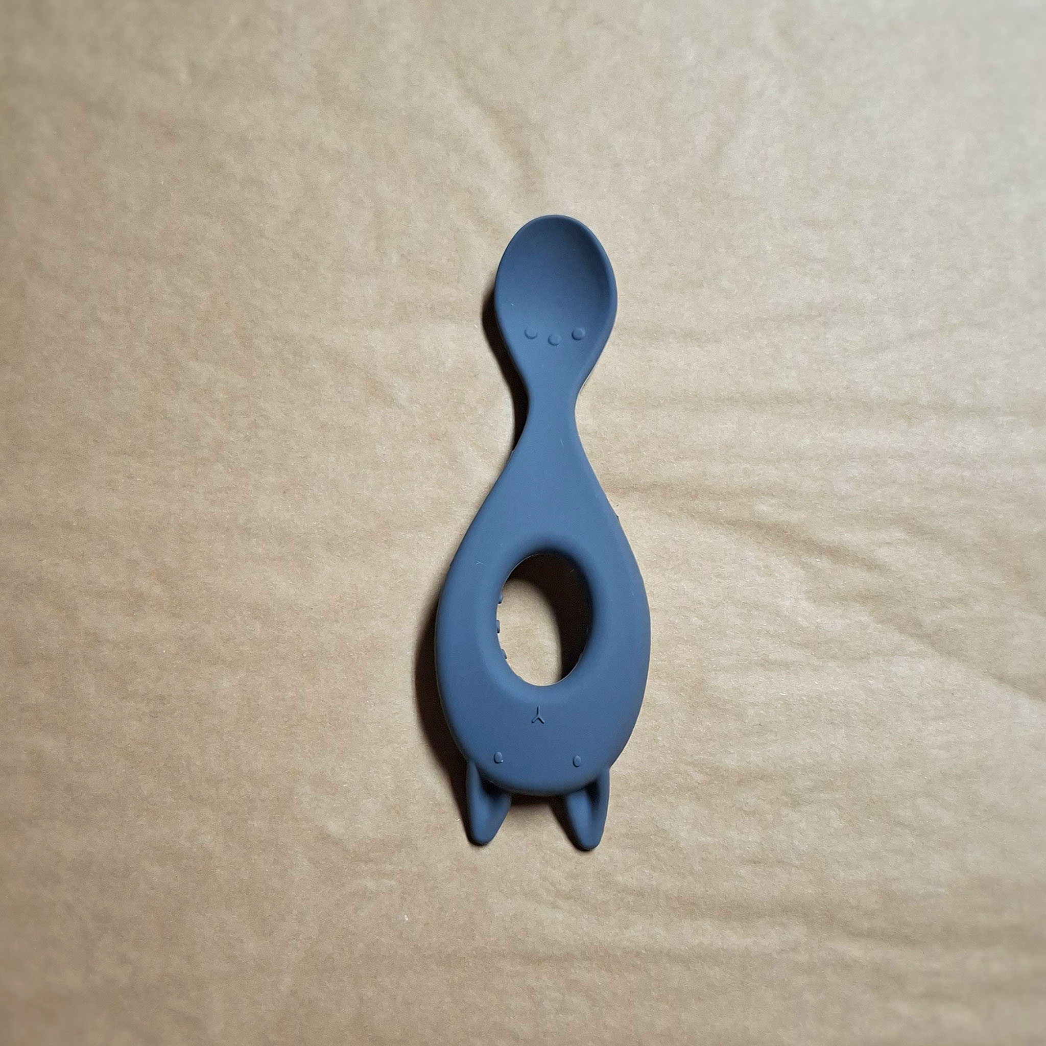 Blue silicone feeding spoon on beige background