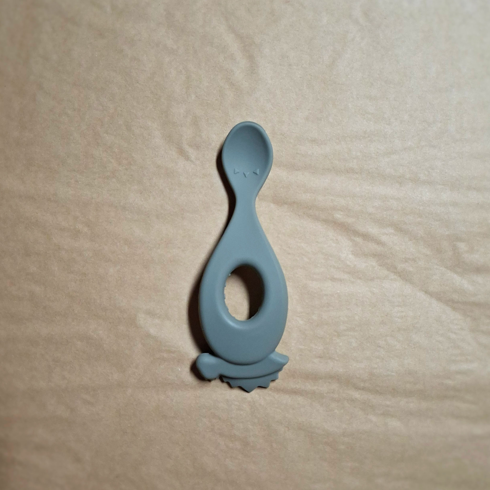 Green silicone feeding spoon on beige background