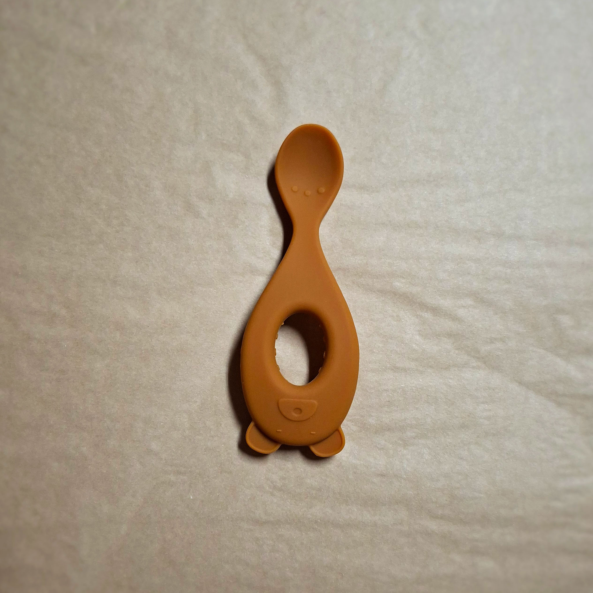 Yellow silicone feeding spoon on beige background